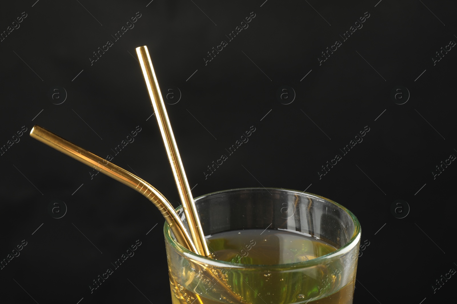 Photo of Tasty refreshing drink with straws in glass on dark background, closeup