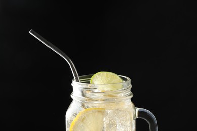 Photo of Tasty refreshing drink with straw in mason jar on dark background, closeup