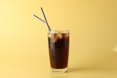 Photo of Tasty refreshing drink with straws in glass on beige background