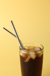 Tasty refreshing drink with straws in glass on beige background, closeup