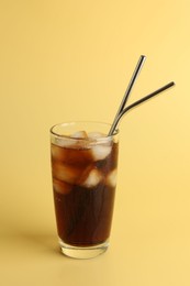 Photo of Tasty refreshing drink with straws in glass on beige background