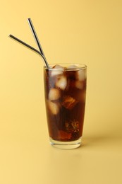 Tasty refreshing drink with straws in glass on beige background