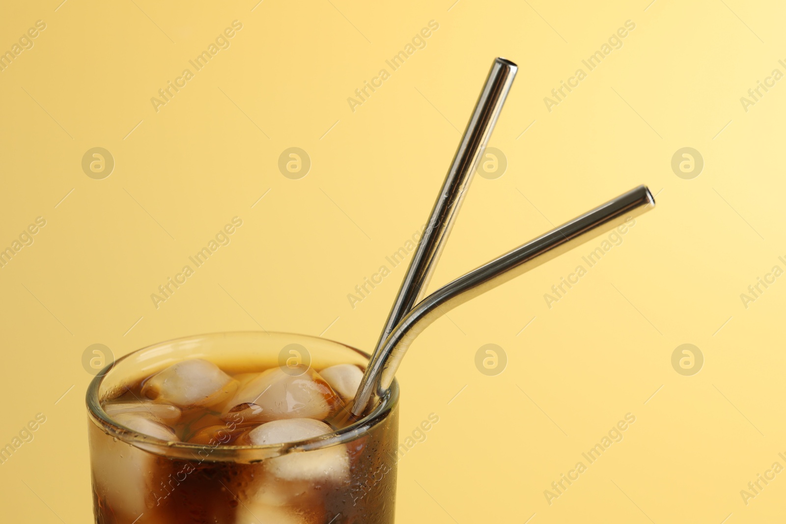 Photo of Tasty refreshing drink with straws in glass on beige background, closeup