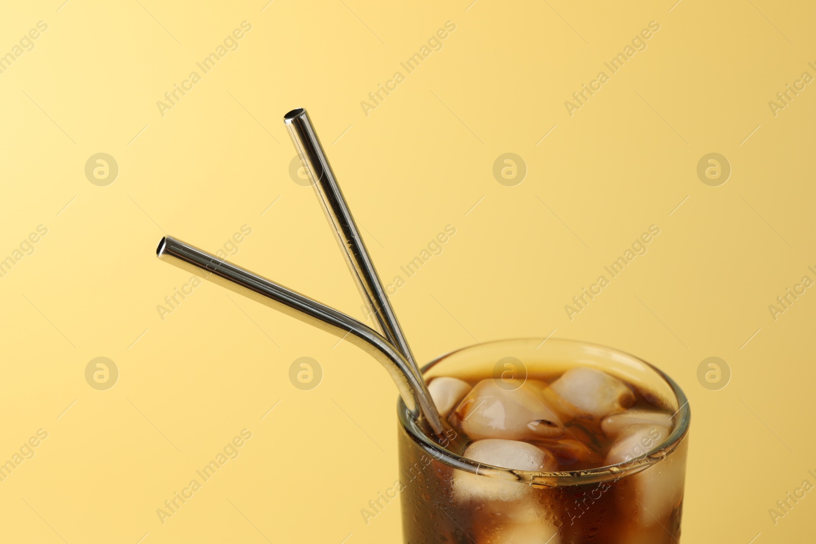 Photo of Tasty refreshing drink with straws in glass on beige background, closeup