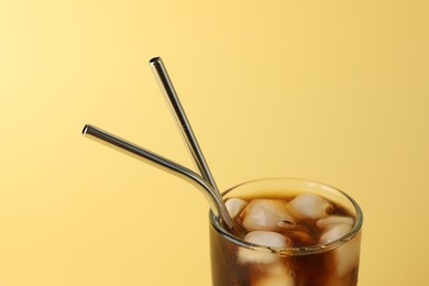 Photo of Tasty refreshing drink with straws in glass on beige background, closeup