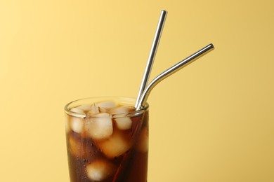 Photo of Tasty refreshing drink with straws in glass on beige background, closeup