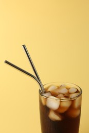 Tasty refreshing drink with straws in glass on beige background, closeup