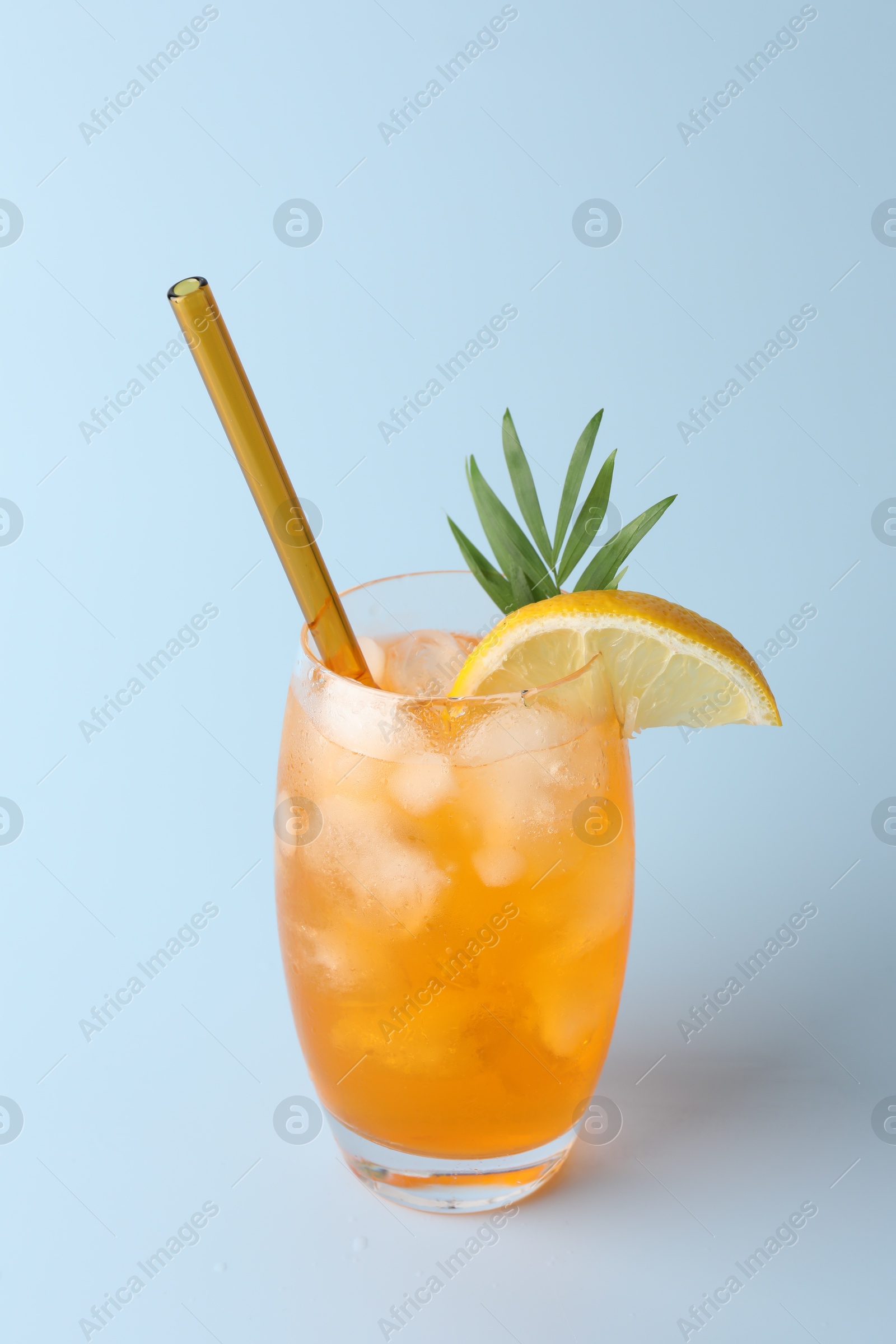 Photo of Tasty refreshing drink with straw in glass on light blue background