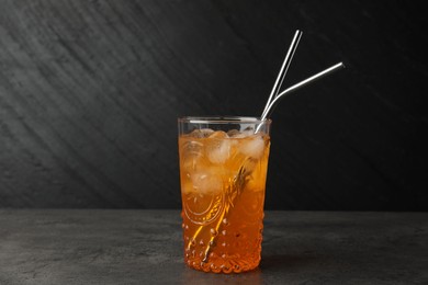 Tasty refreshing drink with straws in glass on grey textured table