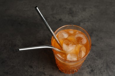 Photo of Tasty refreshing drink with straws in glass on grey table, closeup