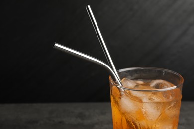 Tasty refreshing drink with straws in glass on dark background, closeup