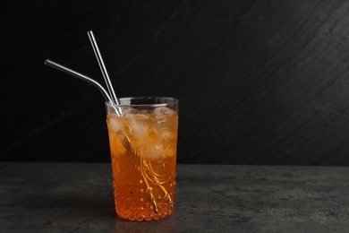 Photo of Tasty refreshing drink with straws in glass on grey textured table, space for text