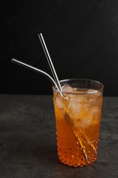 Photo of Tasty refreshing drink with straws in glass on grey textured table