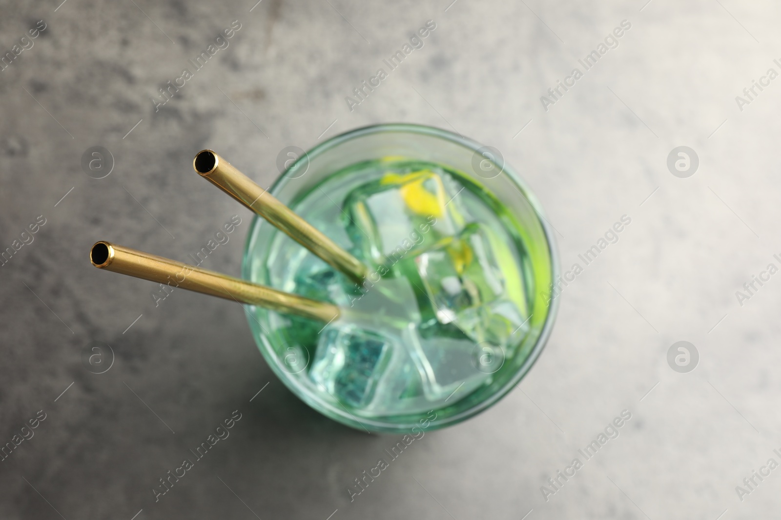 Photo of Tasty refreshing drink with straws in glass on grey table, top view