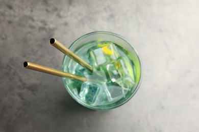 Tasty refreshing drink with straws in glass on grey table, top view