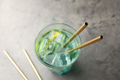 Photo of Tasty refreshing drink with straws in glass on grey table, closeup