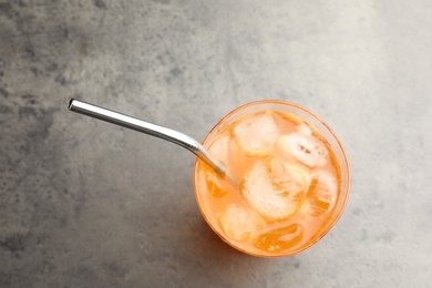 Photo of Tasty refreshing drink with straw in glass on grey table, top view