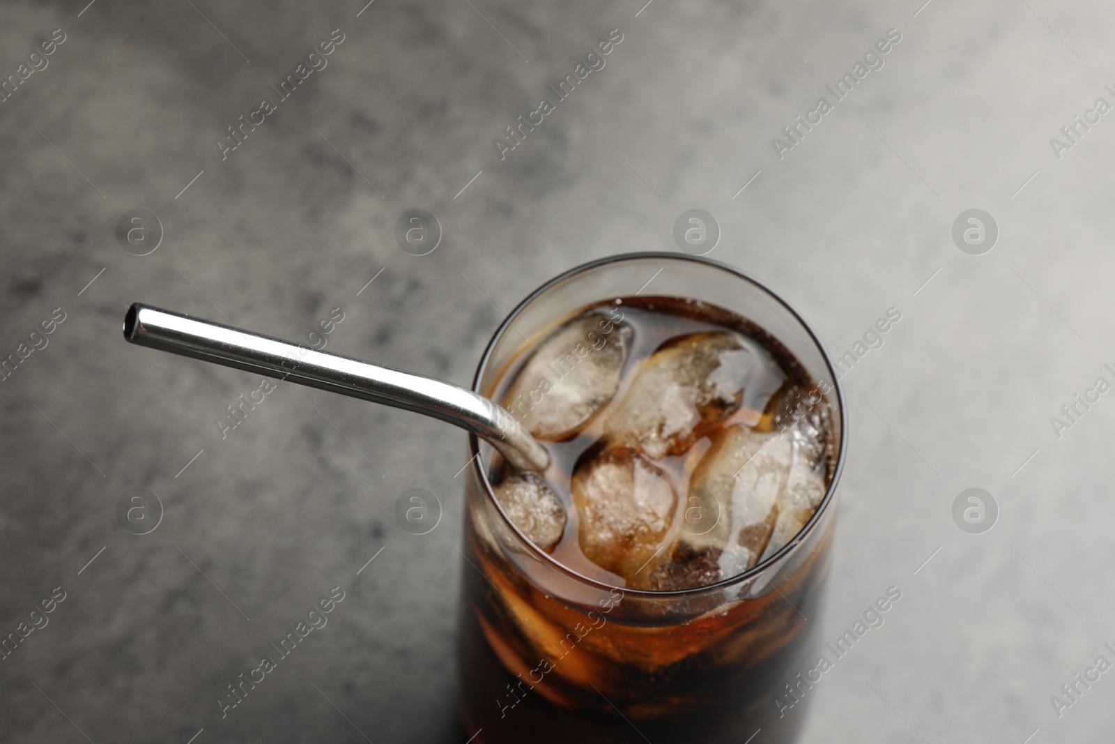 Photo of Tasty refreshing drink with straw in glass on grey table, closeup