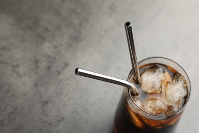 Tasty refreshing drink with straws in glass on grey table, closeup. Space for text