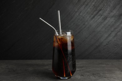 Tasty refreshing drink with straws in glass on grey textured table