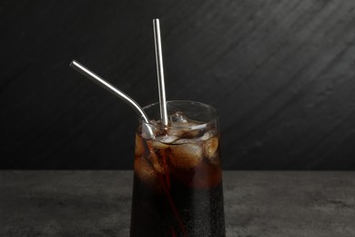 Tasty refreshing drink with straws in glass on grey table