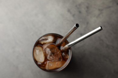 Tasty refreshing drink with straws in glass on grey table, top view