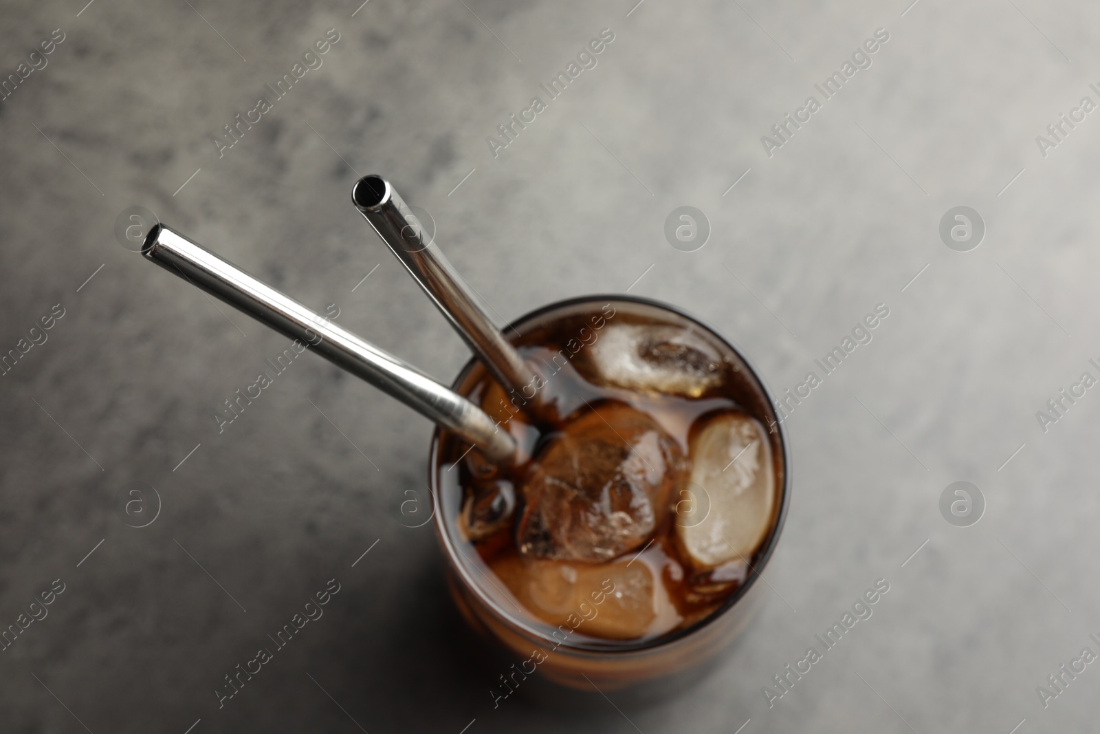 Photo of Tasty refreshing drink with straws in glass on grey table, top view