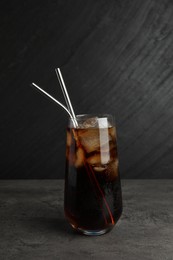 Photo of Tasty refreshing drink with straws in glass on grey textured table