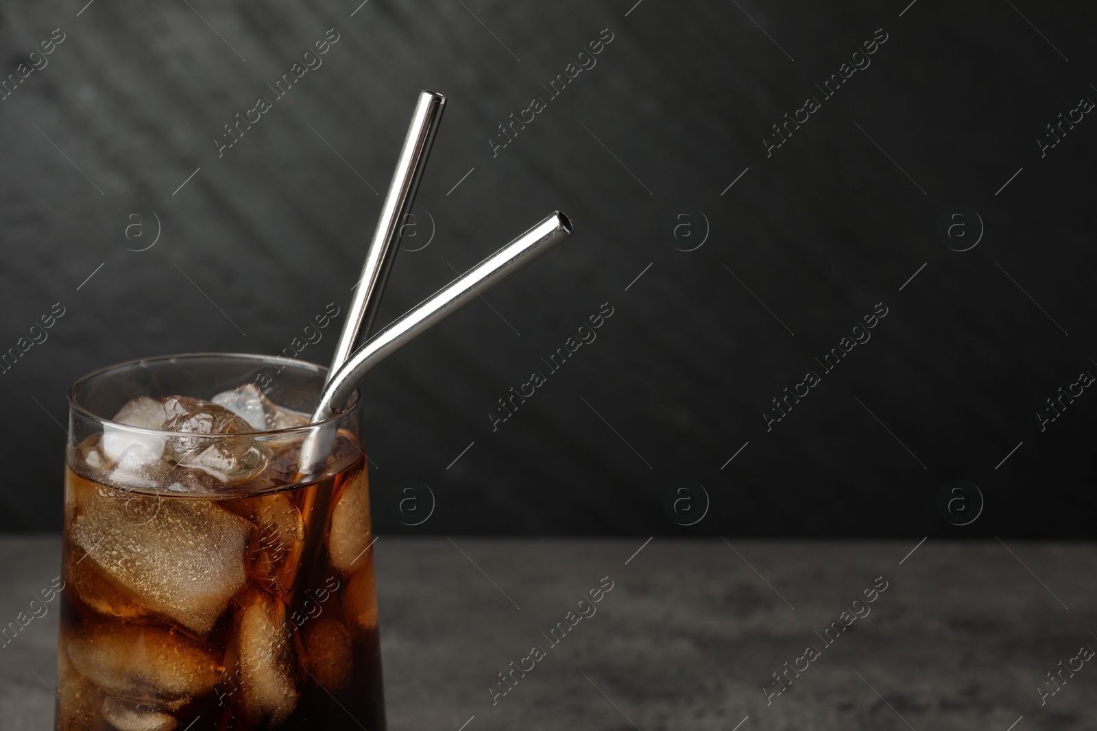 Photo of Tasty refreshing drink with straws in glass on table, closeup. Space for text