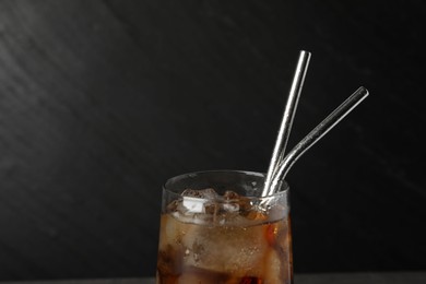 Tasty refreshing drink with straws in glass on dark background, closeup