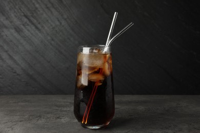 Photo of Tasty refreshing drink with straws in glass on grey textured table