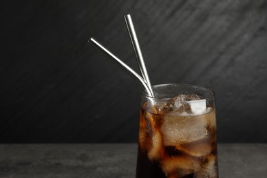 Photo of Tasty refreshing drink with straws in glass on dark background, closeup