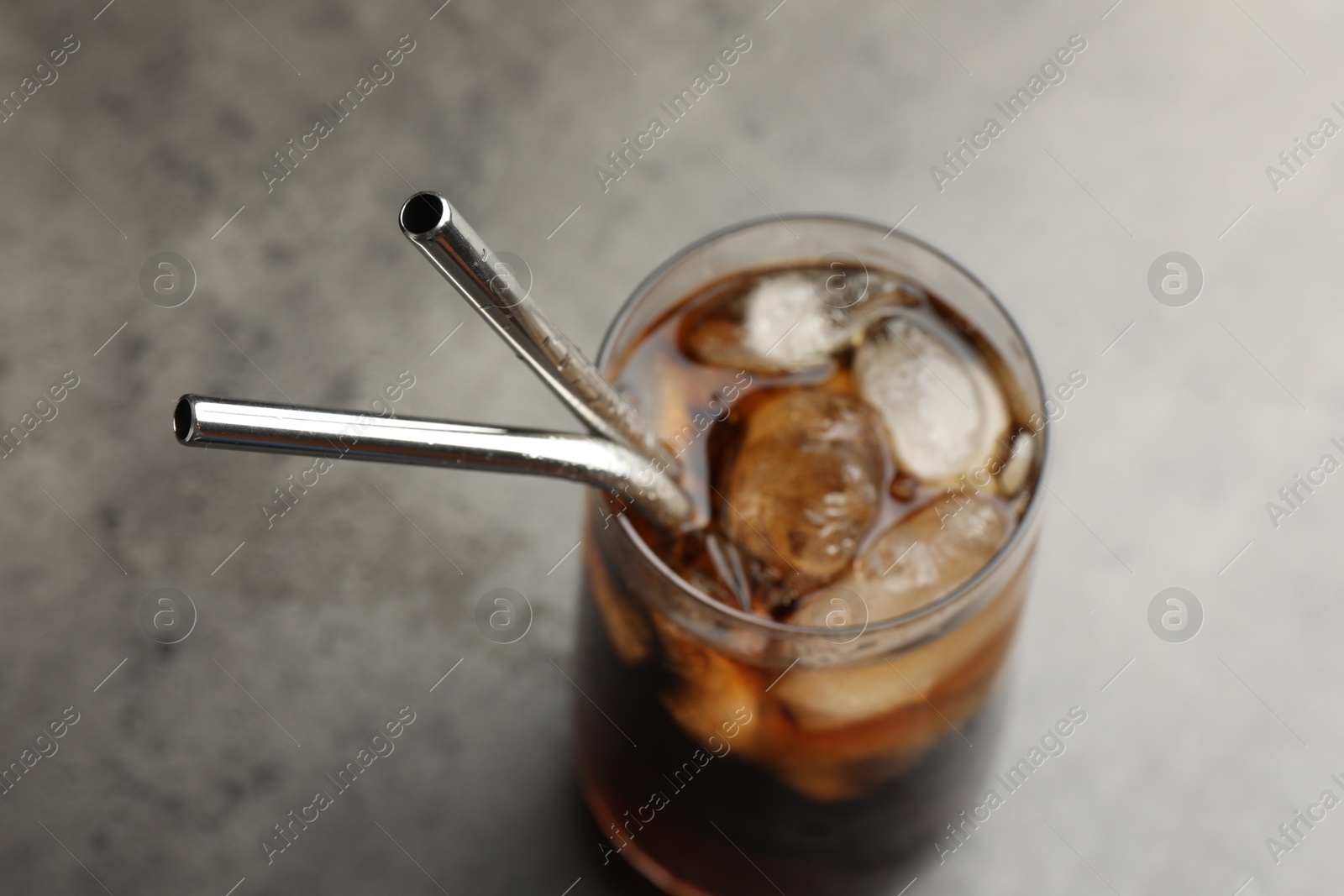 Photo of Tasty refreshing drink with straws in glass on grey table, closeup