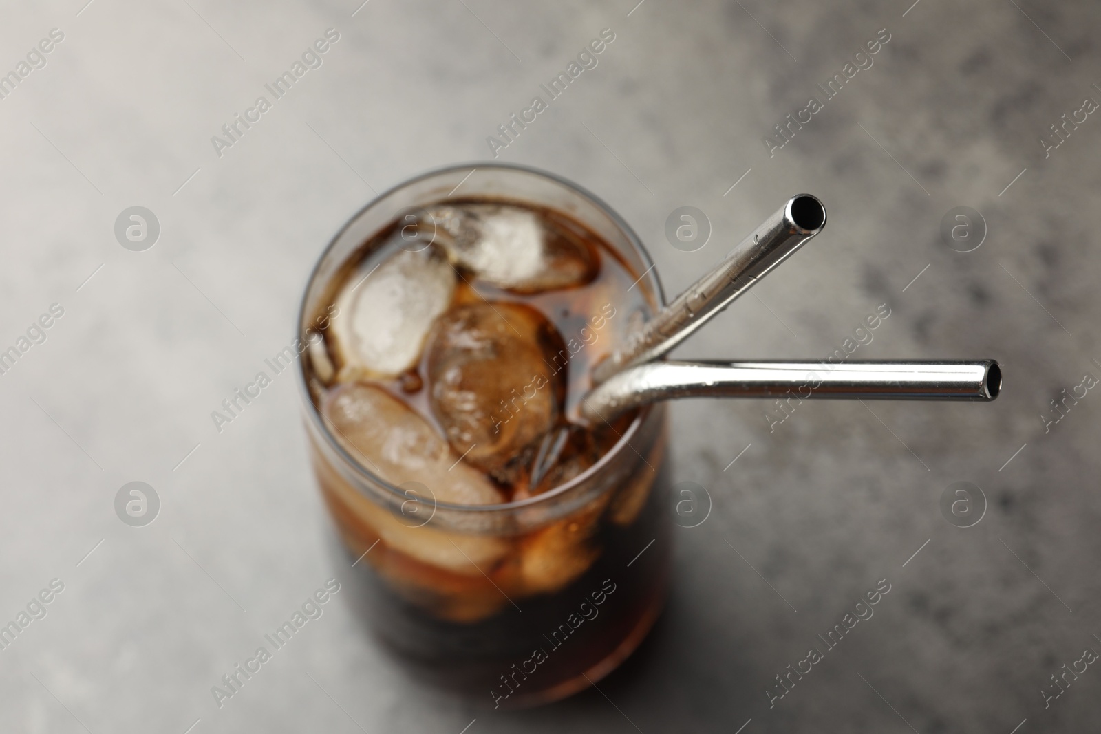 Photo of Tasty refreshing drink with straws in glass on grey table, closeup