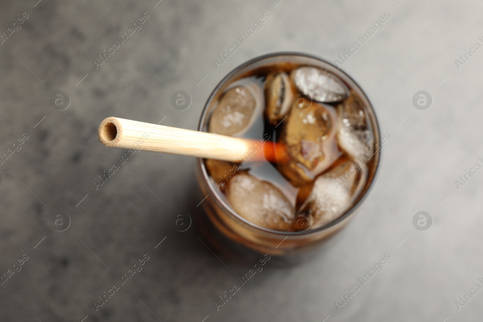 Photo of Tasty refreshing drink with straw in glass on grey table, above view