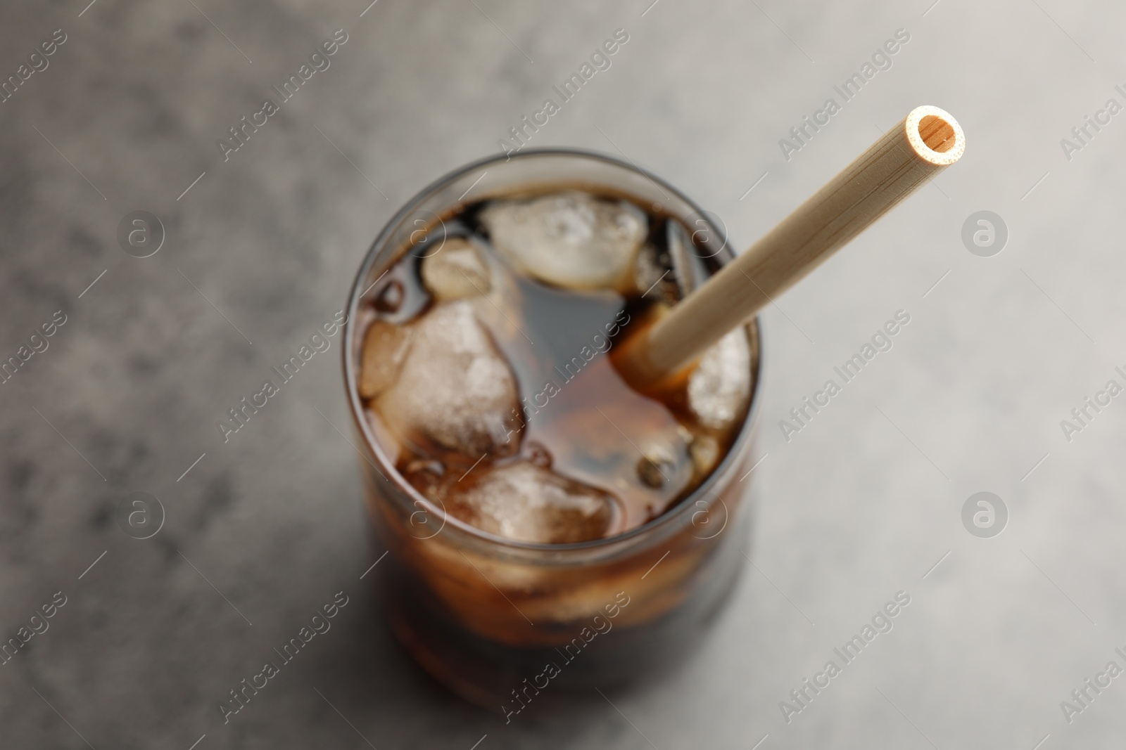 Photo of Tasty refreshing drink with straw in glass on grey table, above view