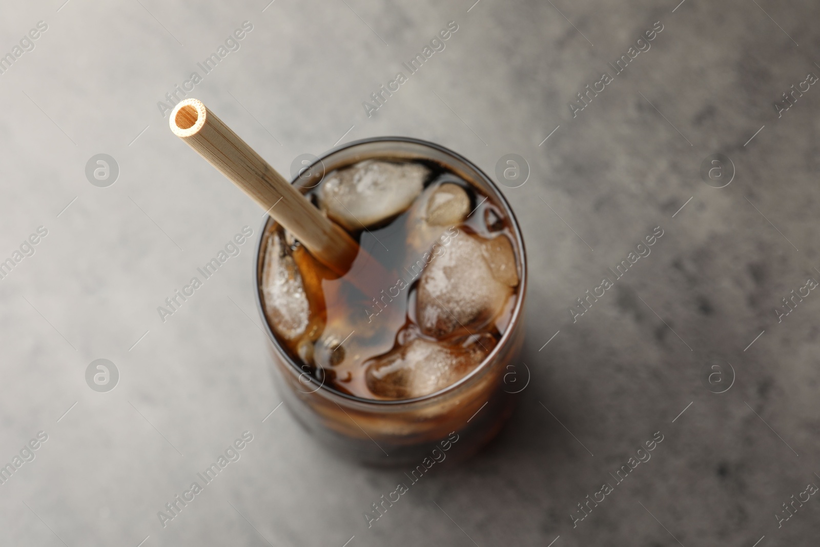 Photo of Tasty refreshing drink with straw in glass on grey table, above view