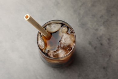 Tasty refreshing drink with straw in glass on grey table, above view