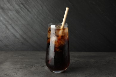 Tasty refreshing drink with straw in glass on grey textured table