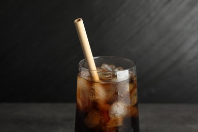 Photo of Tasty refreshing drink with straw in glass on grey table, closeup