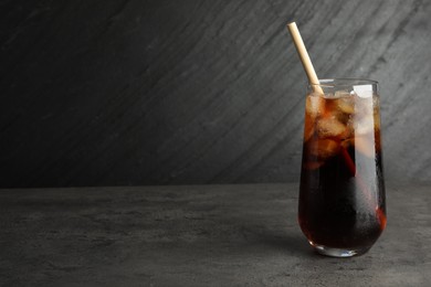 Tasty refreshing drink with straw in glass on grey textured table, space for text