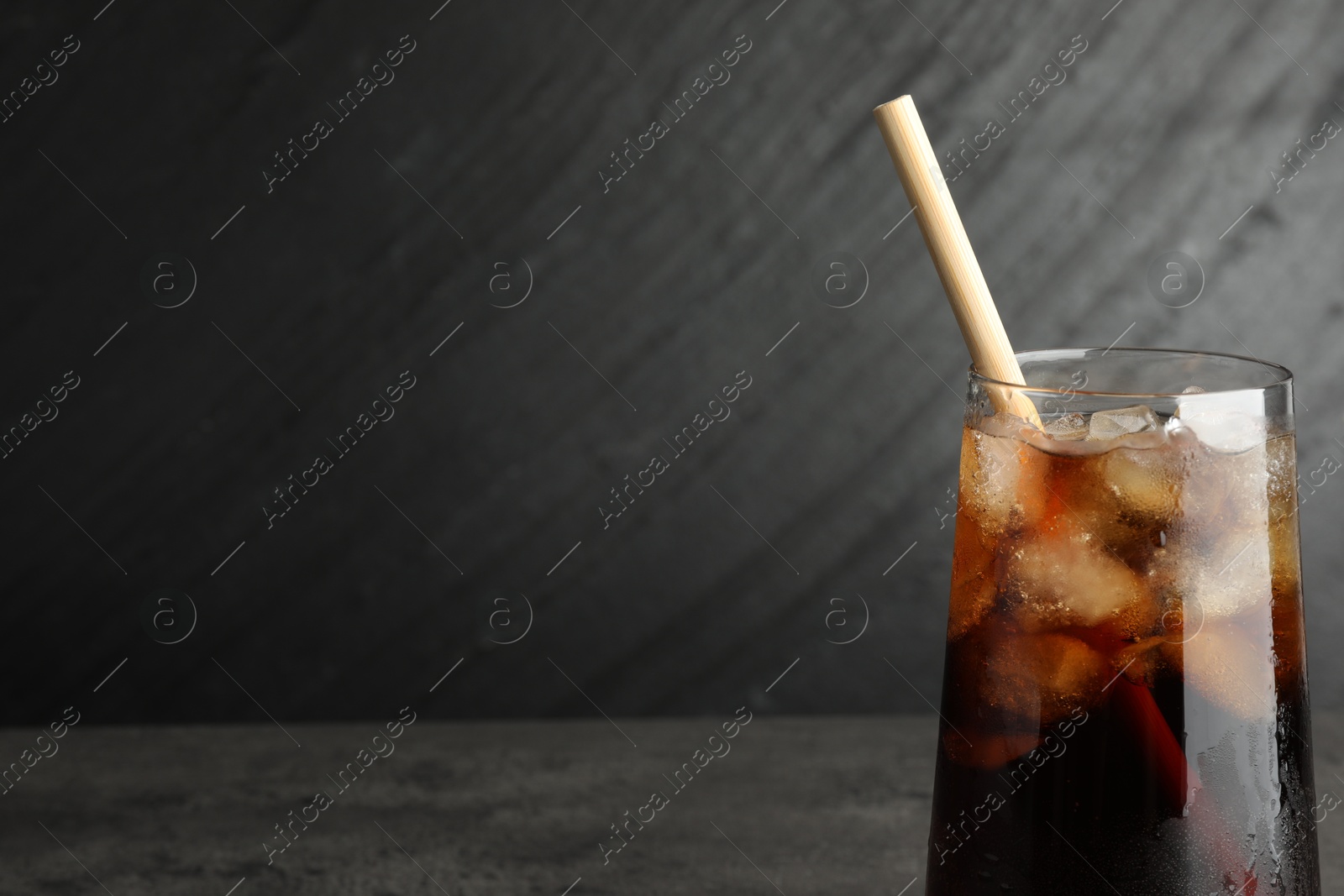 Photo of Tasty refreshing drink with straw in glass on grey table, space for text