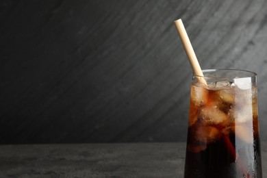 Photo of Tasty refreshing drink with straw in glass on grey table, space for text