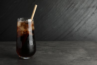 Tasty refreshing drink with straw in glass on grey textured table, space for text