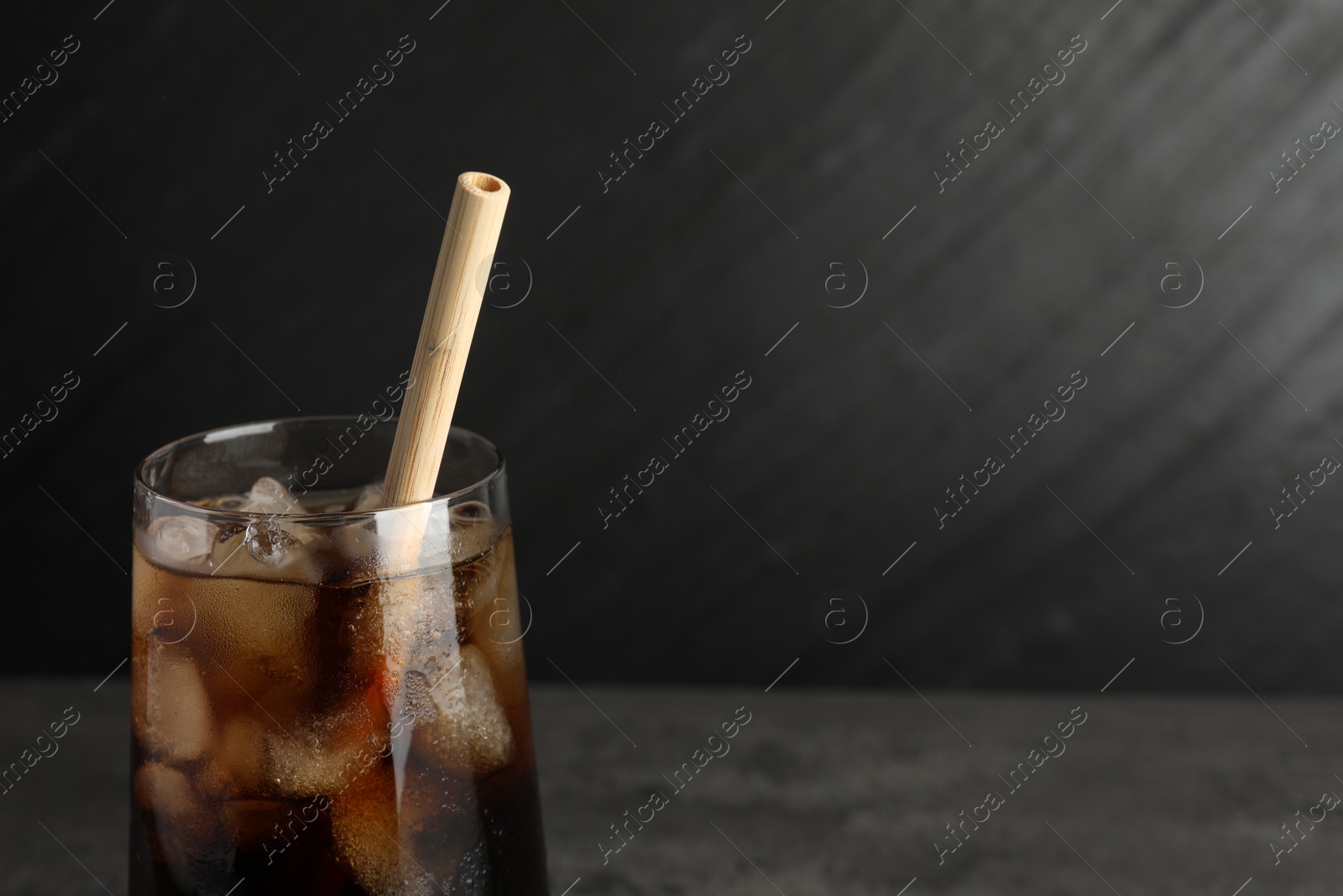 Photo of Tasty refreshing drink with straw in glass on grey table, closeup. Space for text