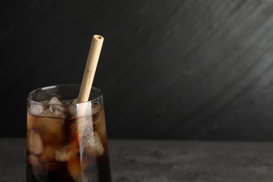 Photo of Tasty refreshing drink with straw in glass on grey table, closeup. Space for text