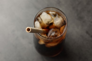 Tasty refreshing drink with straw in glass on grey table, closeup