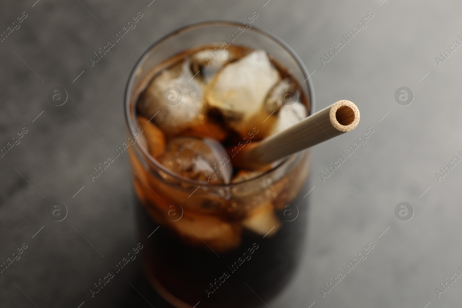 Photo of Tasty refreshing drink with straw in glass on grey table, closeup