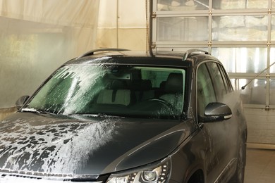 Photo of Washing auto with high pressure water jet at car wash, closeup