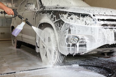 Photo of Man washing auto with high pressure water jet at car wash, closeup